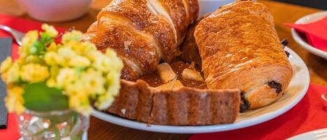 A dining table with a plate of croissants and a bowl of fruit.