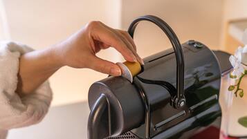 A hand operating a coffee machine with a cup placed underneath.