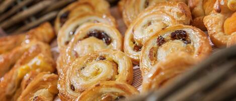 A variety of pastries, including cinnamon rolls and other baked goods, displayed on a table.