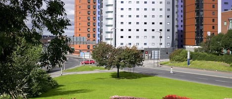 A hotel with a modern design, featuring a central courtyard with flower beds and a tree.