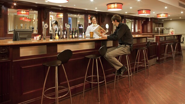 A bar area with stools, a counter, and a bartender.
