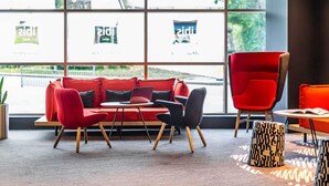 A modern interior with a red sofa set, a red armchair, and a small table with a laptop.