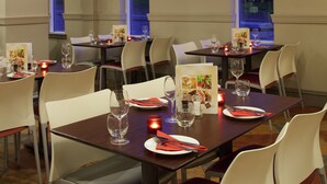 A restaurant with tables set for dining, featuring menus, wine glasses, and candles.