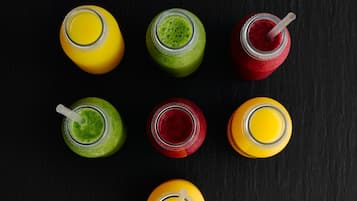 Zes glazen smoothies op een zwarte ondergrond.