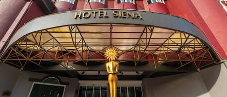 The entrance of Hotel Siena with a distinctive golden sun sculpture.