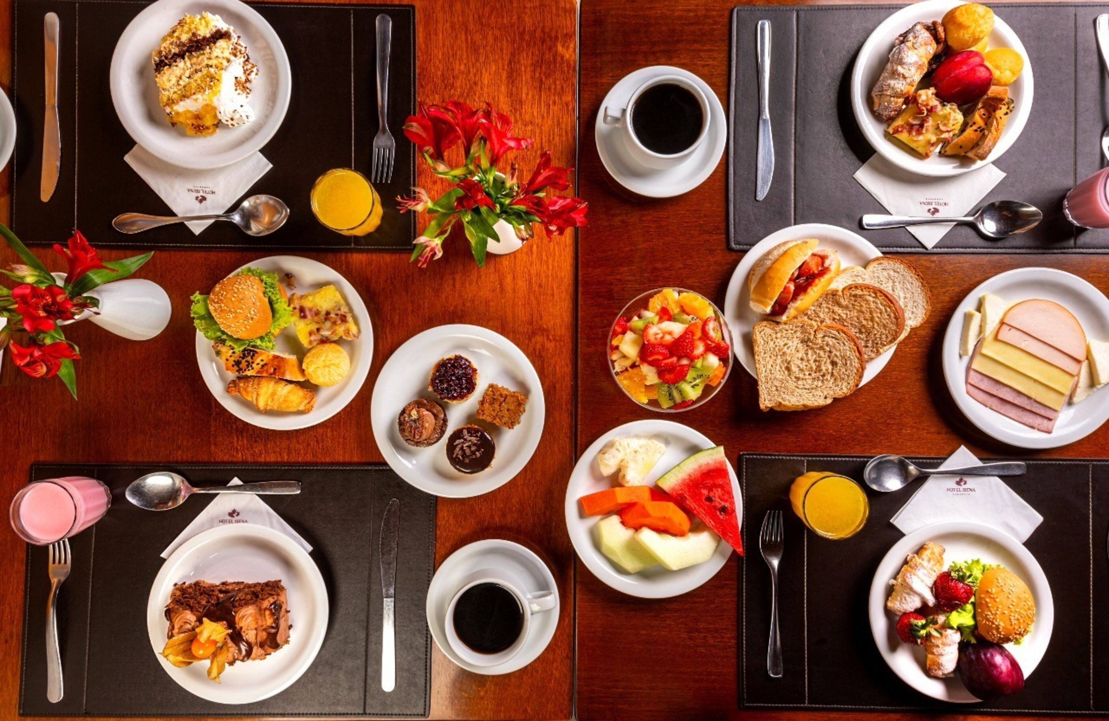 A breakfast buffet with various dishes, including fruits, pastries, and sandwiches, arranged on a wooden table.