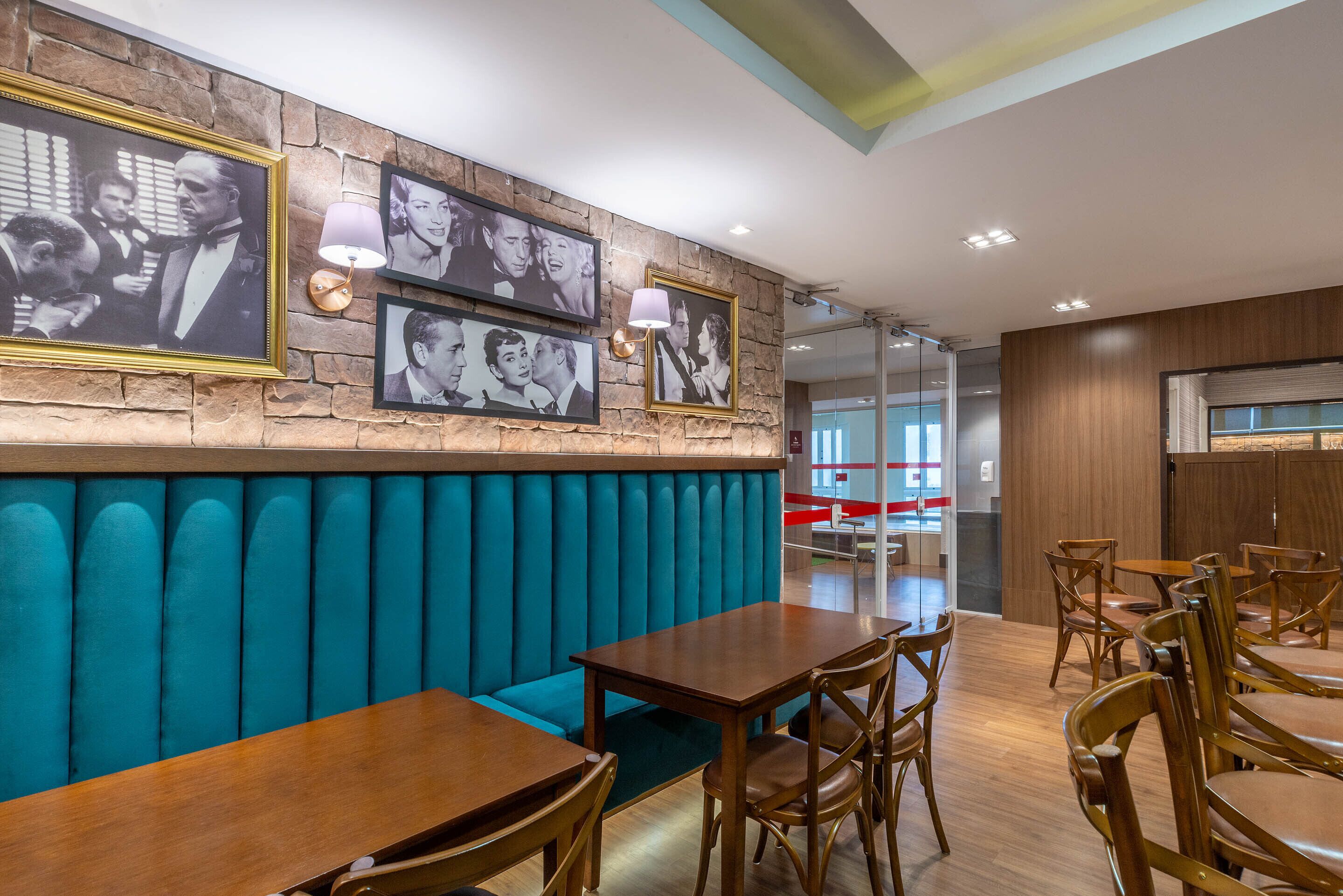 A restaurant with teal booths, wooden tables, and framed black-and-white photographs on the wall.