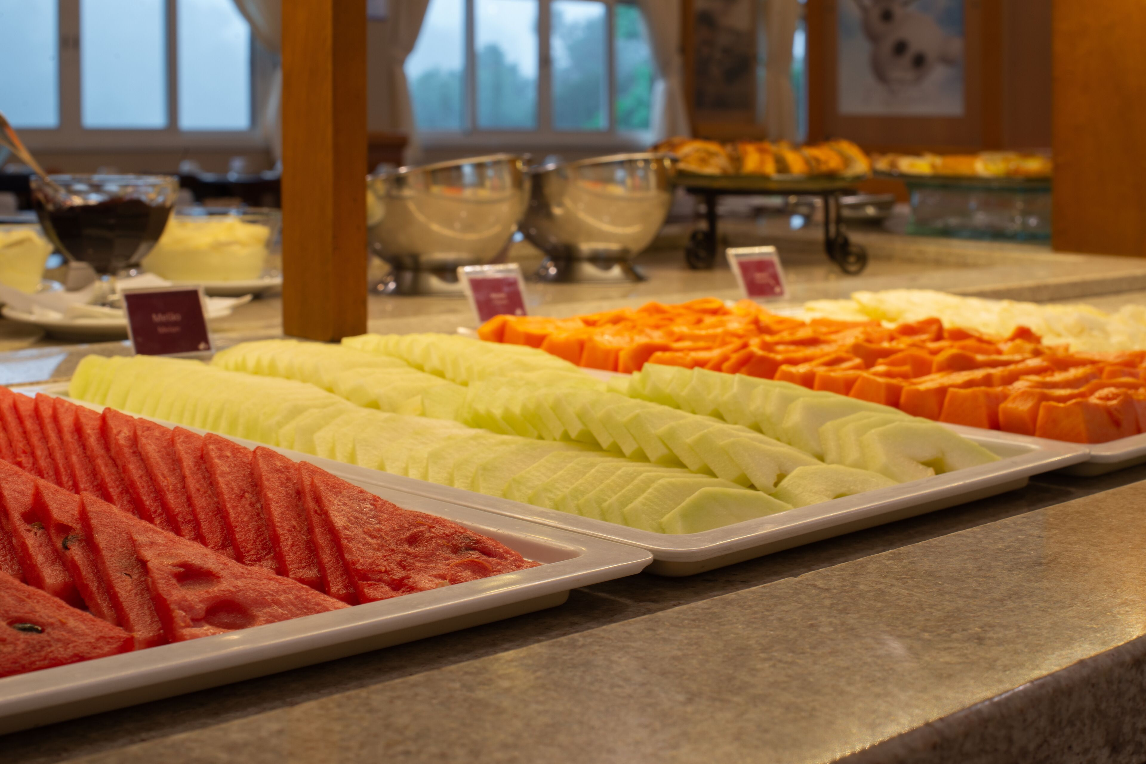 A buffet with neatly arranged fruit trays including watermelon, cantaloupe, and honeydew melon.