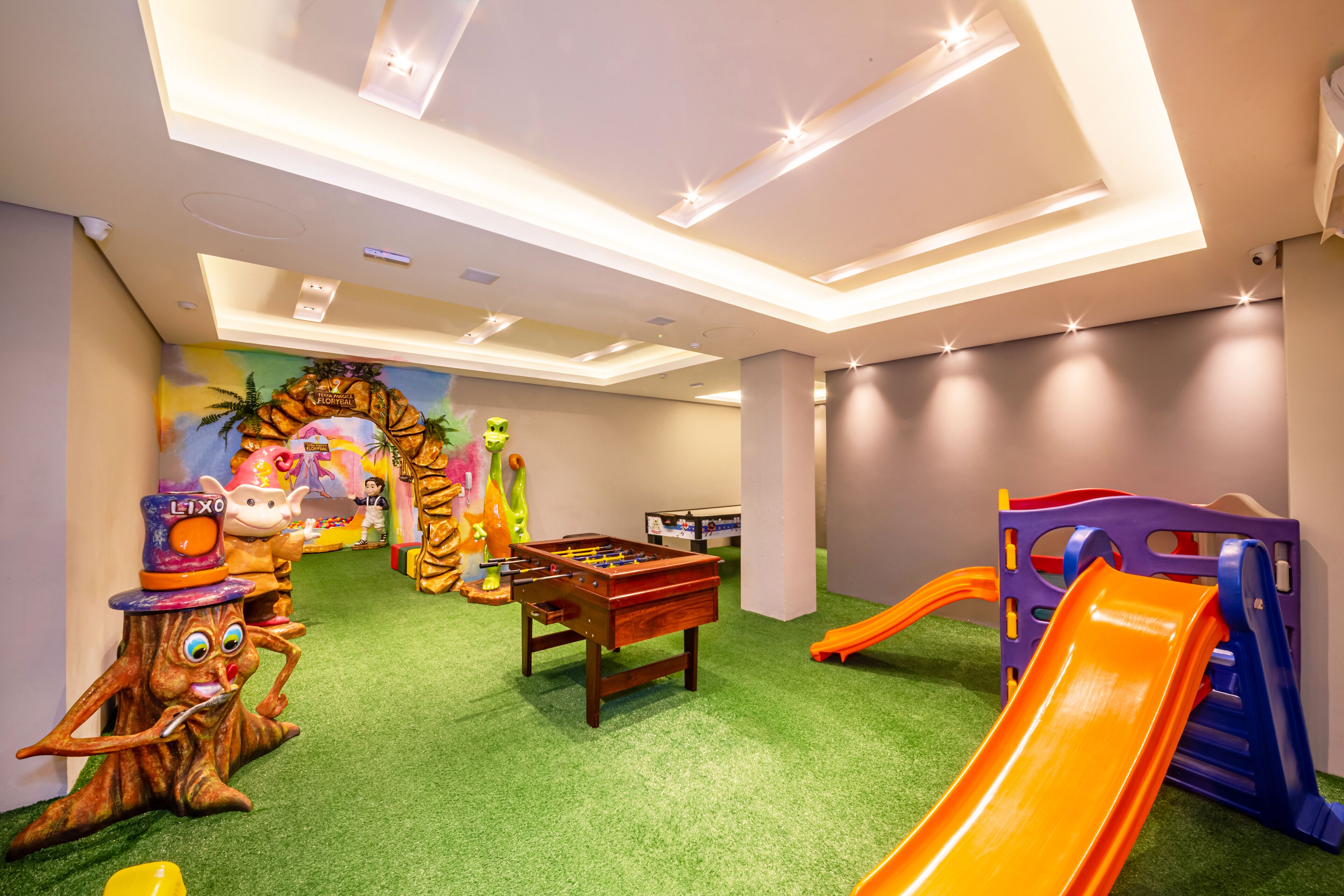 A children's play area with a foosball table, a slide, and various toys.