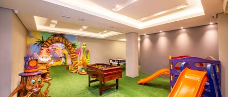 A children's play area with a foosball table, a slide, and various toys.