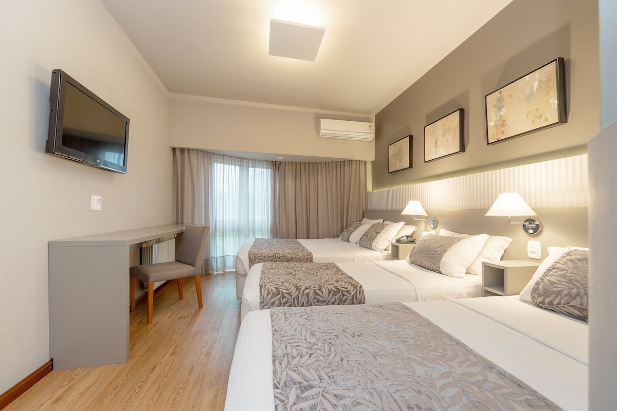 A hotel room with a TV, two beds, a desk, and a chair.