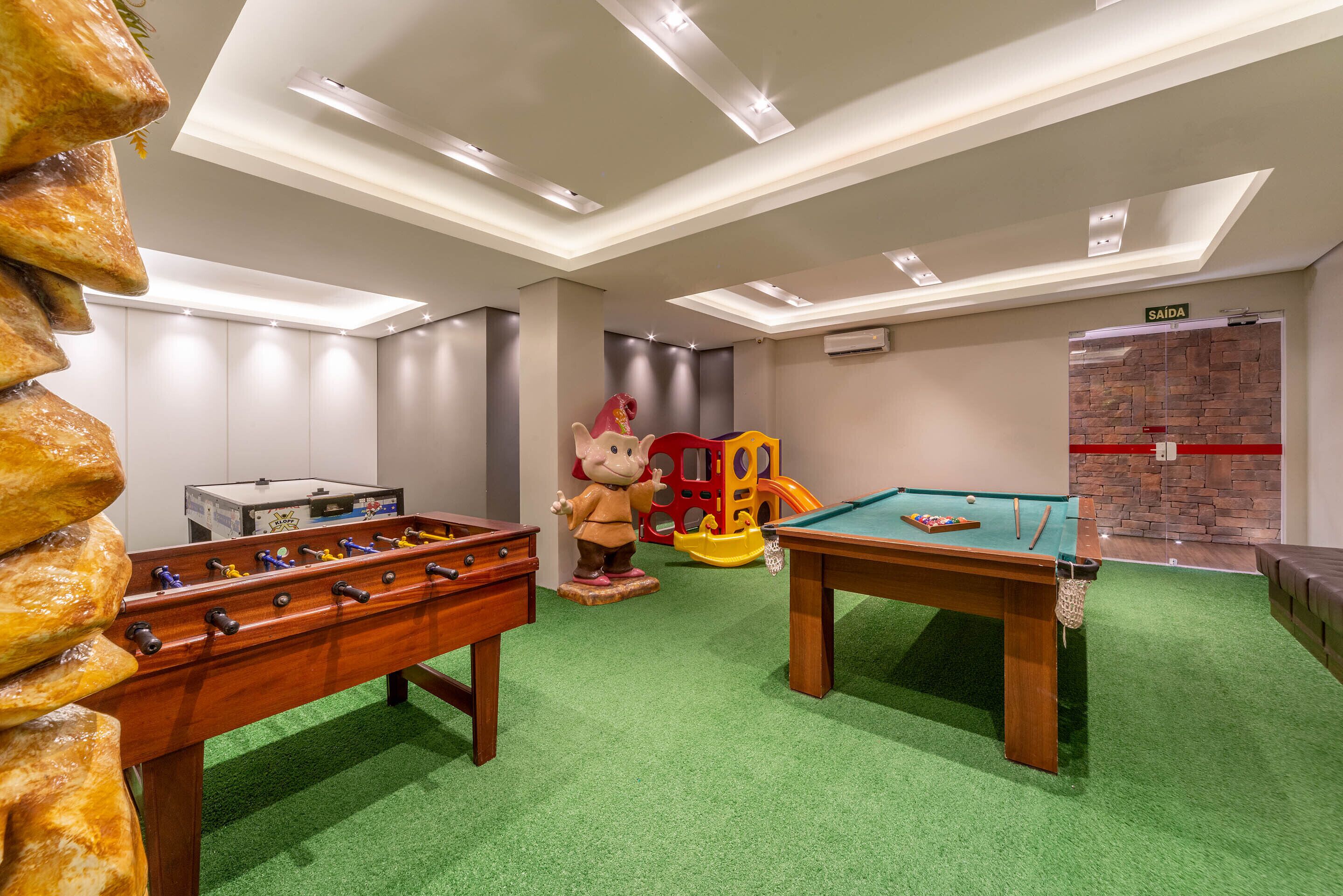 A children's play area with a foosball table, a pool table, and a play structure.