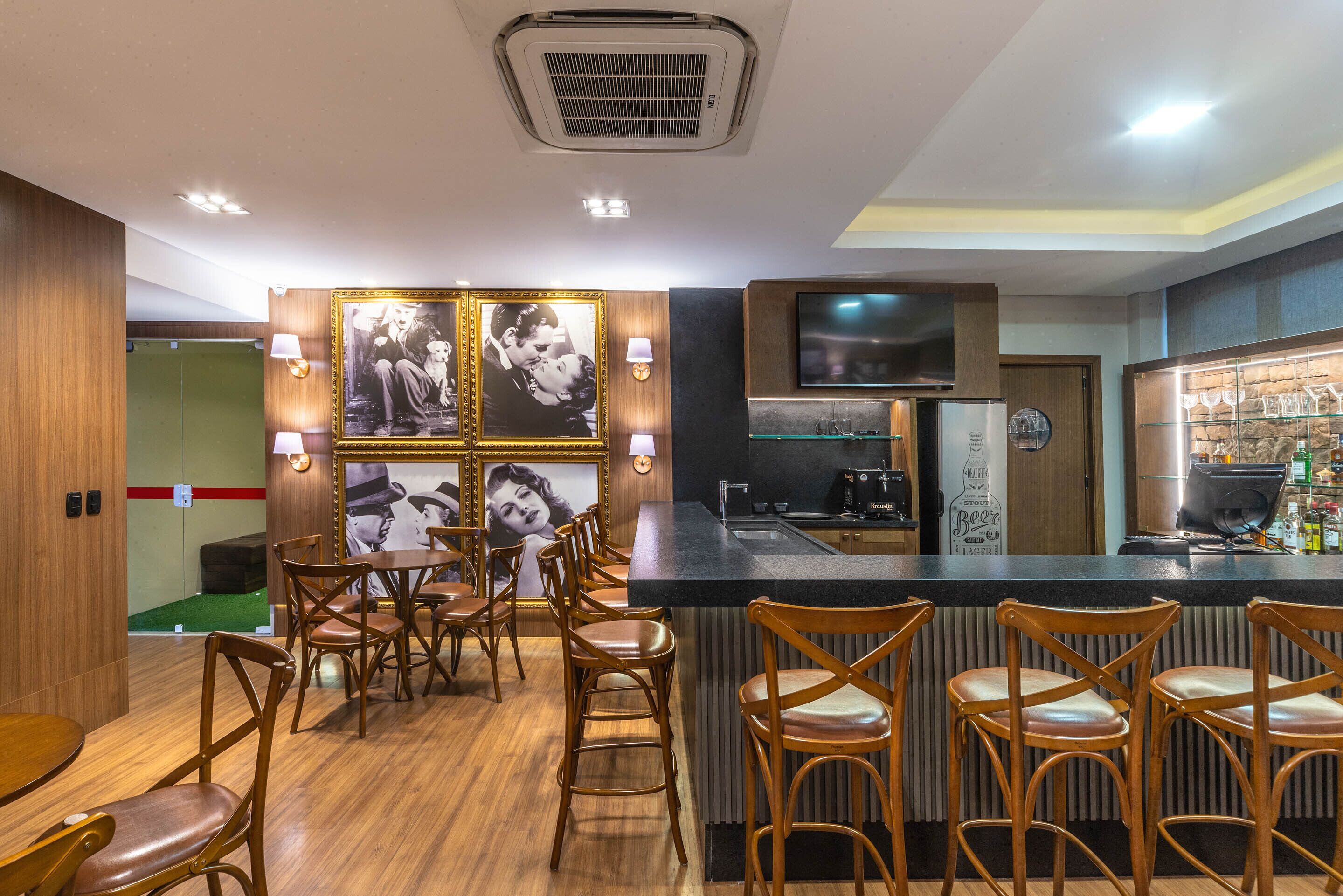 A bar area with wooden chairs, a counter, and framed pictures on the wall.