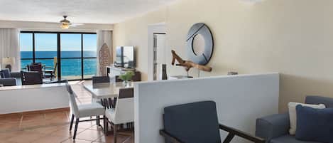 A modern hotel room with a balcony, a dining area, and a seating area with a view of the ocean.