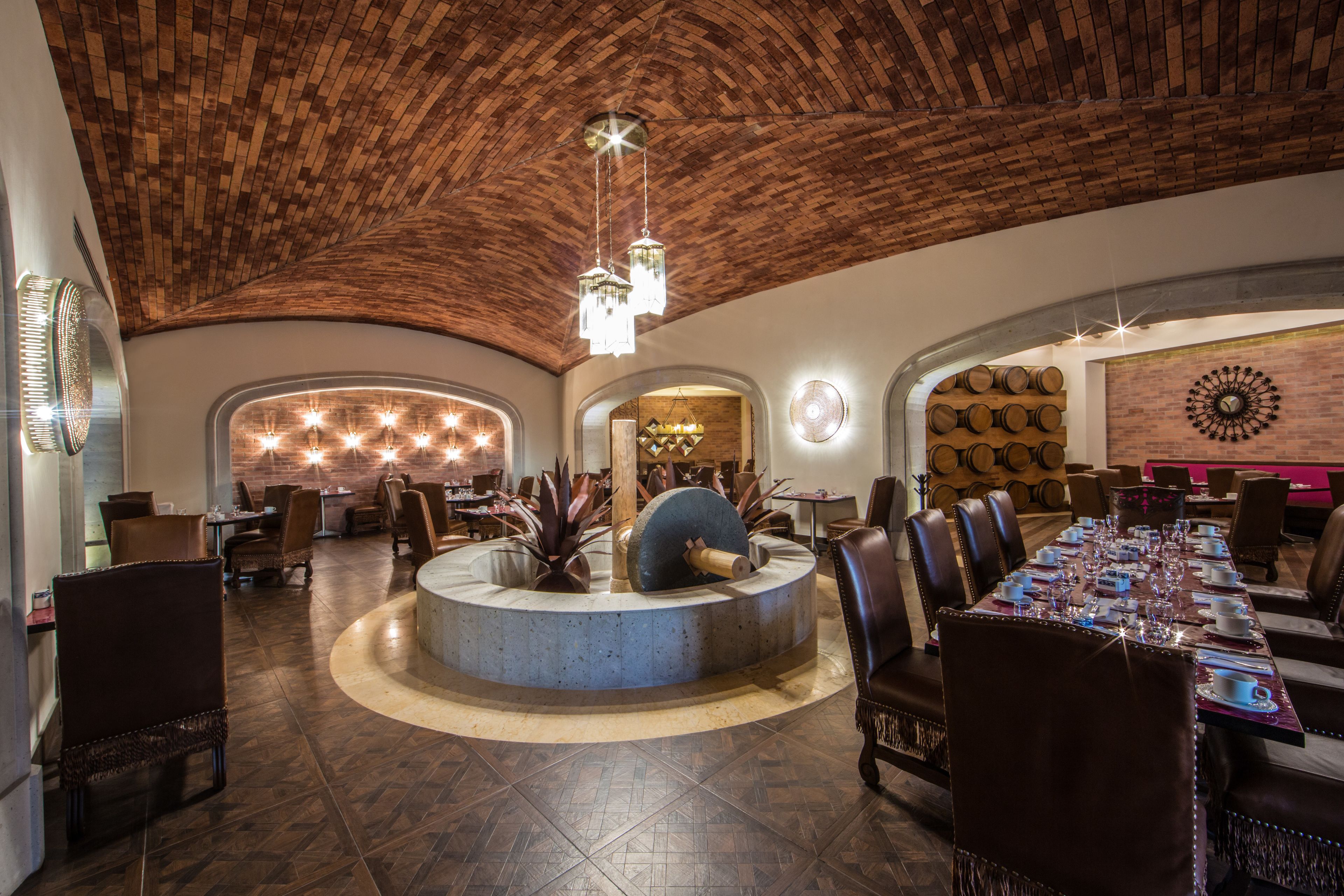 Un restaurante espacioso con un alto techo de ladrillo y una zona de bar central.