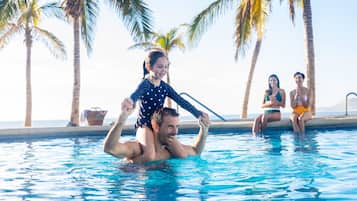 Guests can enjoy a refreshing swim in the pool surrounded by palm trees and the ocean.