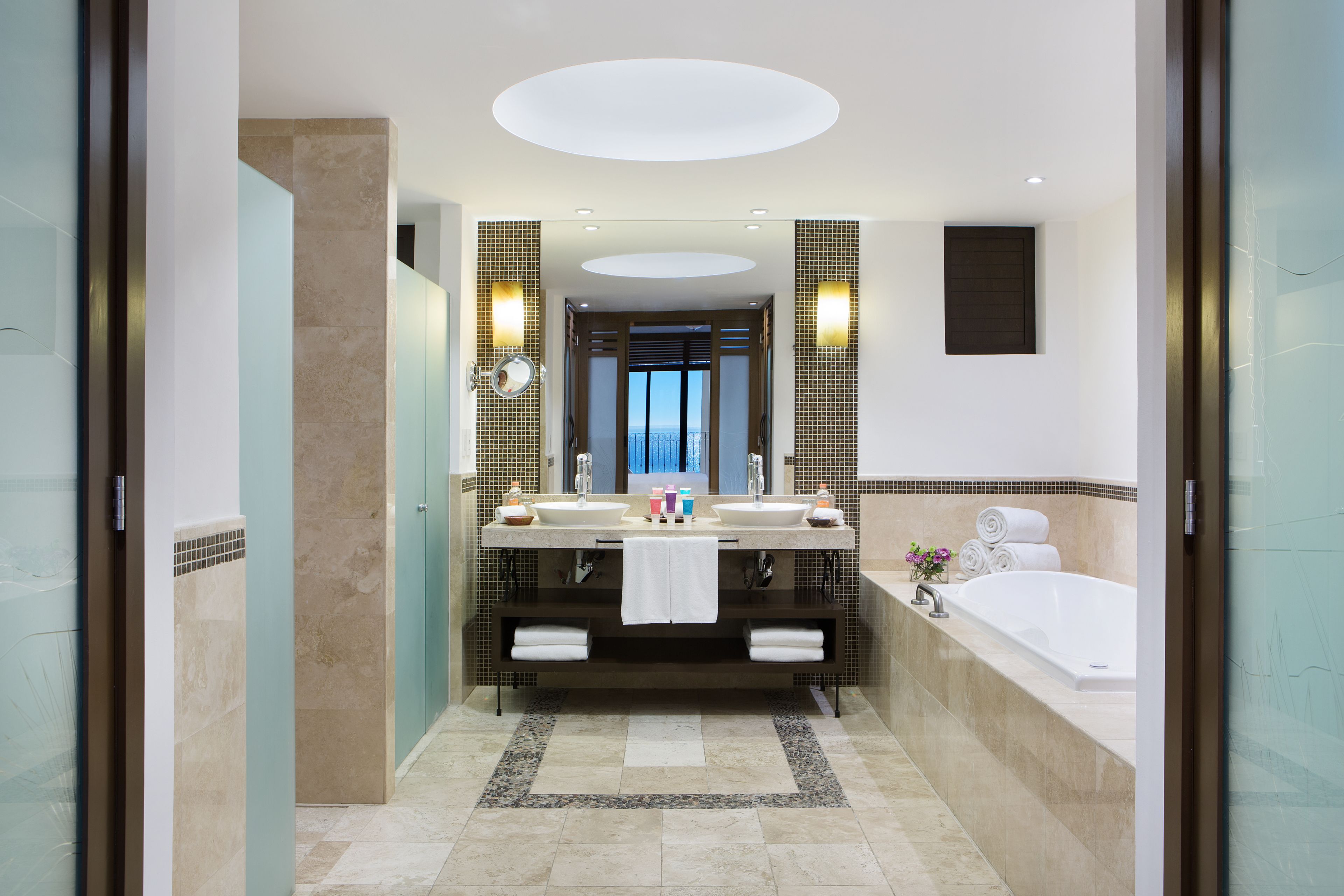 Un baño moderno con lavamanos doble, un espejo grande y una bañera.