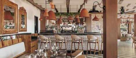 A restaurant with a bar area, wooden furniture, and terracotta pendant lighting.