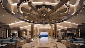 Um hall amplo com design circular central, várias áreas de estar e vista para o mar.