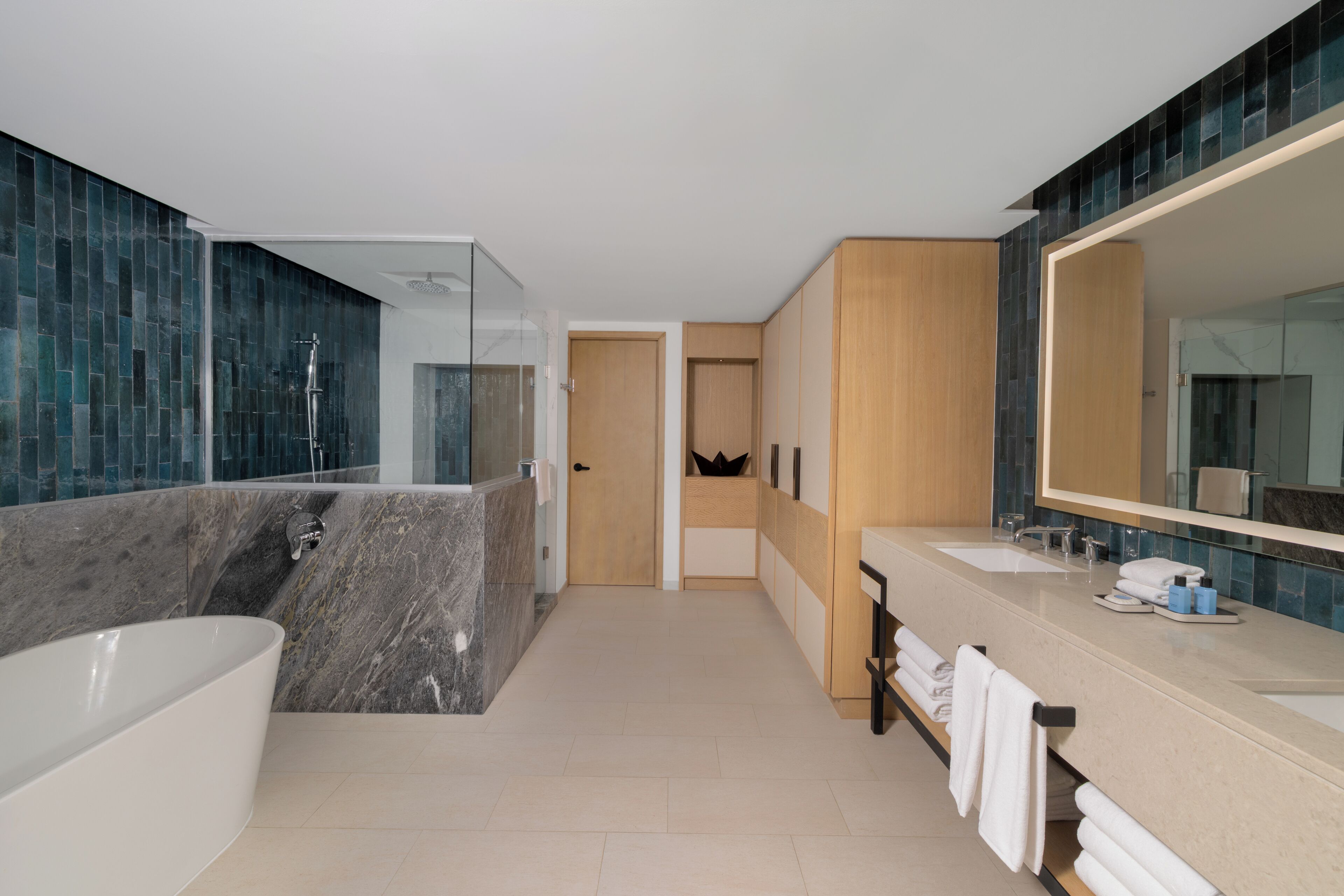 A modern bathroom with a large bathtub, two sinks, and a walk-in shower.