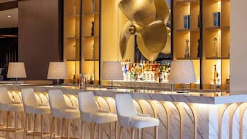 A bar area with marble countertops, bar stools, and a large decorative fan.