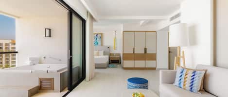 A modern hotel room with a balcony, a sofa, a dining table with fruit, a bed, and a wardrobe.