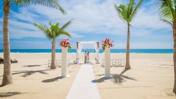 Decoración para boda en la playa, con un pasillo blanco y adornos florales.