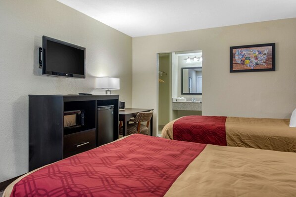A hotel room with two beds, a desk, a TV, a microwave, and a bathroom visible through an open door. - Econo Lodge Freeport - Brunswick Area (Freeport)