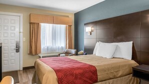 A hotel room with a large bed, a bedside table, a chair, a window with curtains, and a door. - Econo Lodge Freeport - Brunswick Area (Freeport)