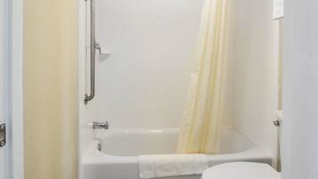 A bathroom with a bathtub, toilet, and a shower curtain.