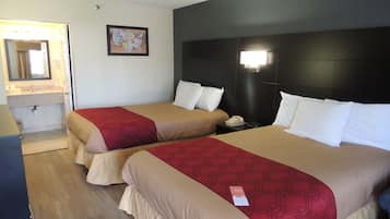 A hotel room with two beds, a nightstand with a phone, a mirror, and a wall-mounted light.