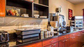 Montaje tipo bufé con una máquina de café, un mostrador de comida y un refrigerador.