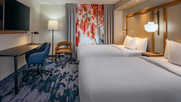 A hotel room with a bed, a desk, a chair, a TV, and a large window with curtains. - Fairfield Inn & Suites by Marriott Brunswick Freeport (Brunswick)
