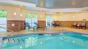 A swimming pool with lounge chairs and tables, surrounded by walls with wooden panels and windows. - Fairfield Inn & Suites by Marriott Brunswick Freeport (Brunswick)