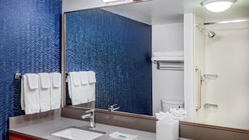 A modern bathroom with a large mirror, a sink, and a shower area.