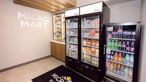 Un MicroMart con dispensadores de bebidas refrigeradas y estantes llenos de aperitivos y bebidas.