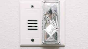 Detector de humo instalado en una pared blanca.