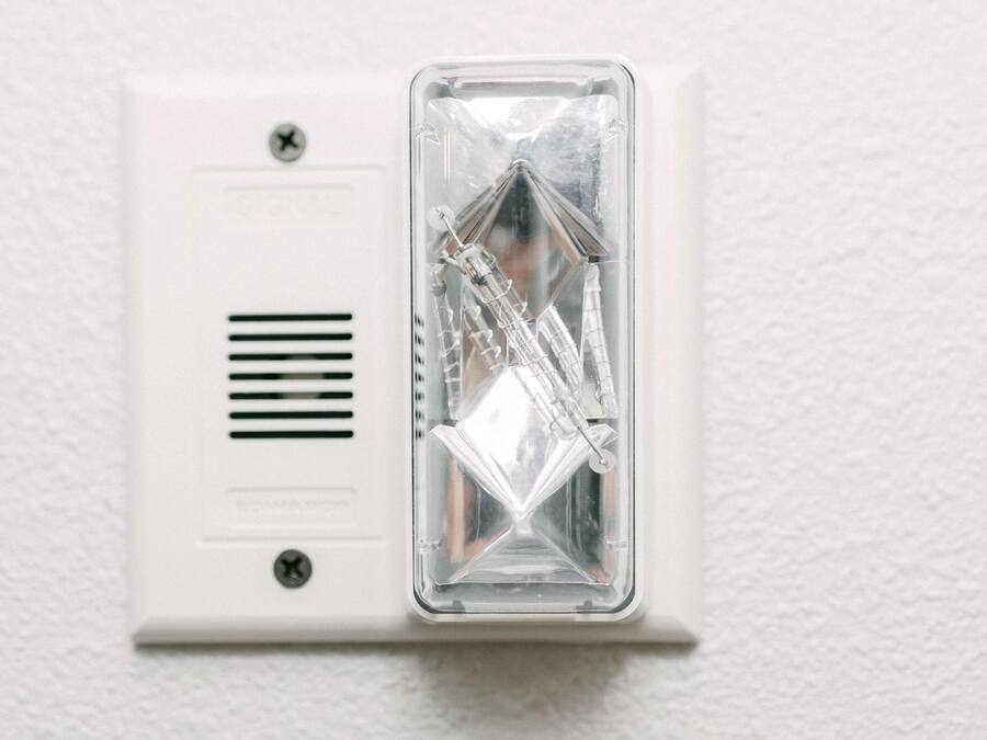 Detector de humo instalado en una pared blanca.