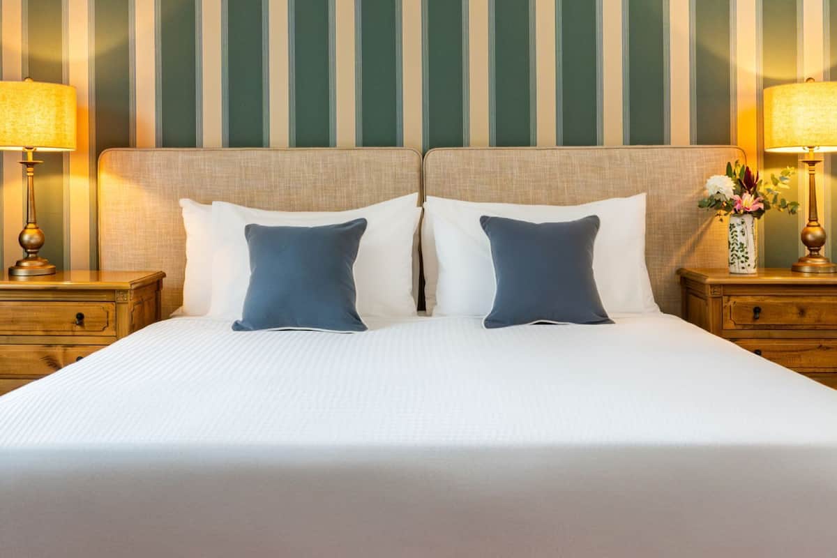 A double bed with two nightstands, each with a lamp and a vase of flowers.