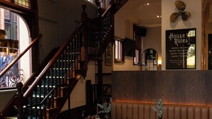 Een restaurantinterieur met houten vloeren, een trap en zithoeken.