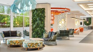 A modern lobby with seating areas, a vertical garden, and large windows. - Danubius Hotel Annabella (Balatonfured)