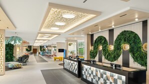 A modern hotel lobby with a reception desk, seating area, and a large wall decorated with greenery. - Danubius Hotel Annabella (Balatonfured)