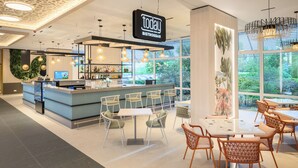 A modern bistro bar with a bar counter, seating area, and large windows. - Danubius Hotel Annabella (Balatonfured)