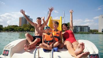 A group of people on a boat with a clear view of the water and buildings in the background.