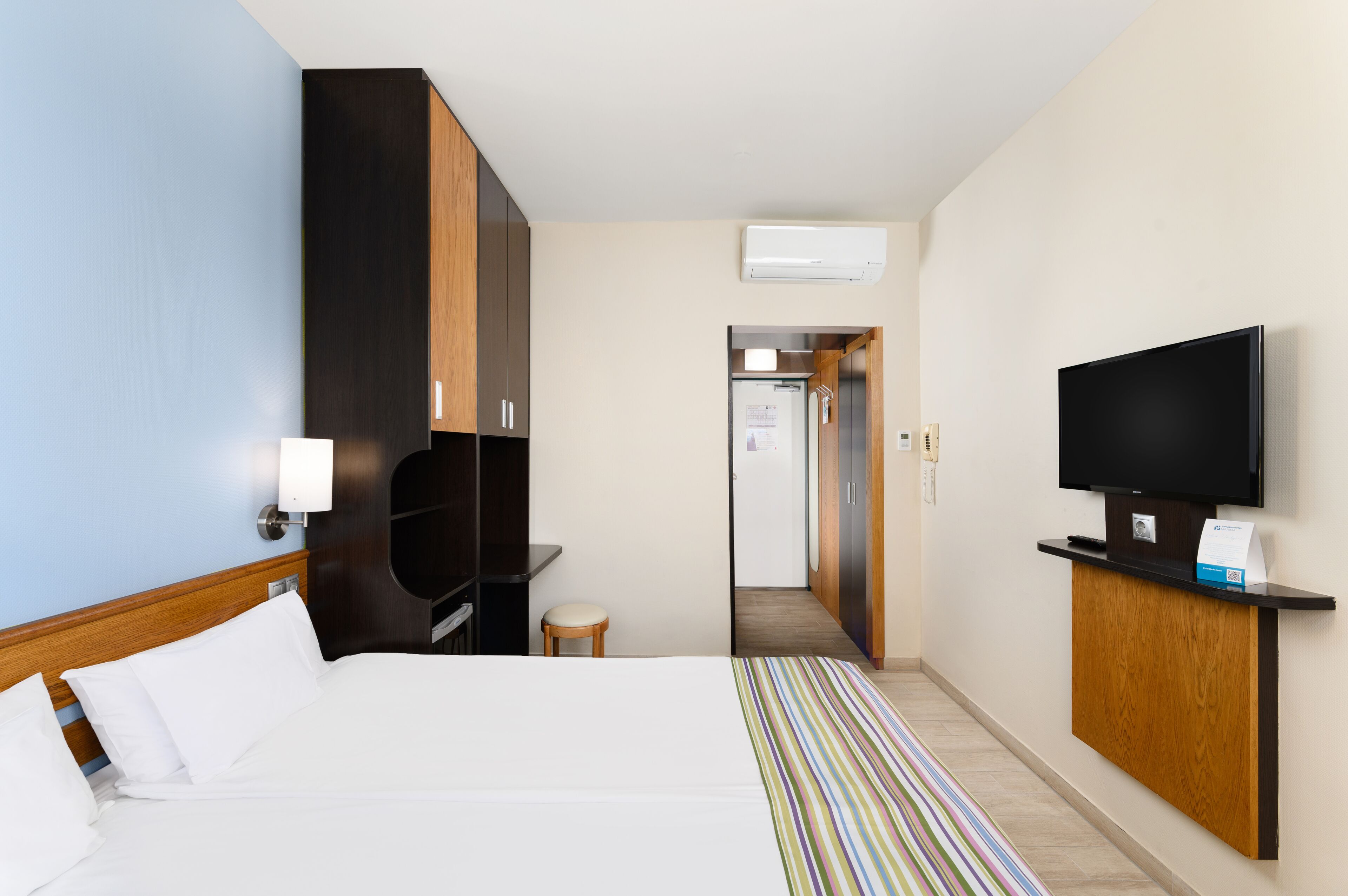 Una habitación de hotel con cama, televisión, escritorio y armario.