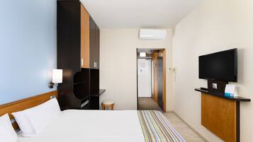 Una habitación de hotel con cama, televisión, escritorio y armario.