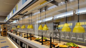 Un espace buffet proposant différents stands de restauration, avec notamment des salades, des fruits et d’autres plats.