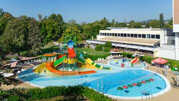 A water park with a large pool, slides, and a building in the background.