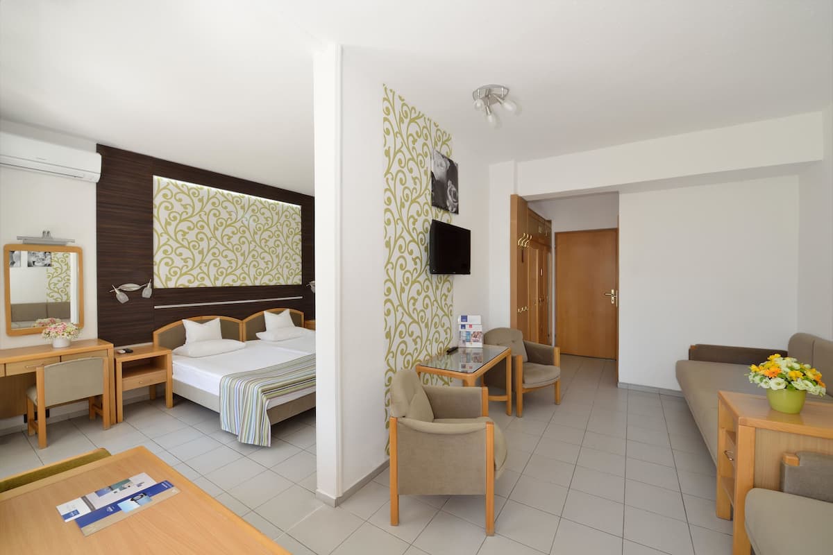 Ein Hotelzimmer mit Bett, Schreibtisch, Stühlen, Fernseher und einer Couch.