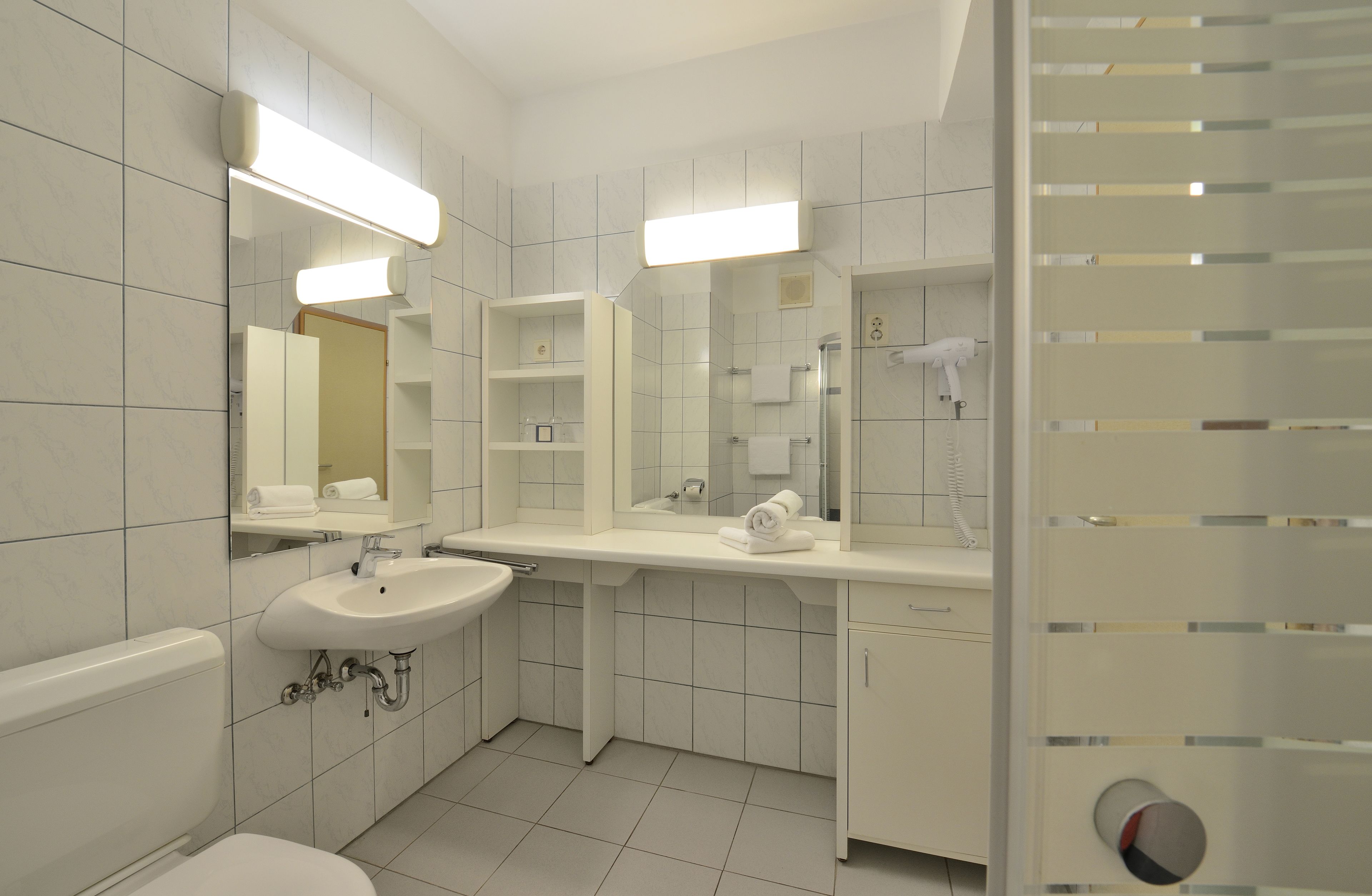 A modern bathroom with a toilet, sink, and mirror.
